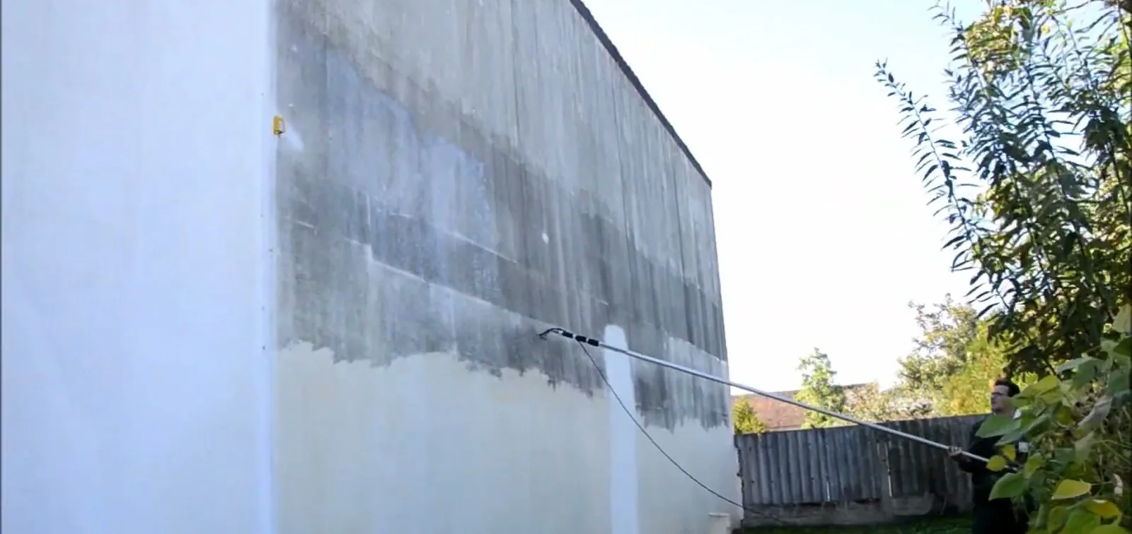 Vorbehandlung einer Giebelwand mit der Teleskoplanze: die behandelte Flaeche hebt sich hell vom Bewuchs ab